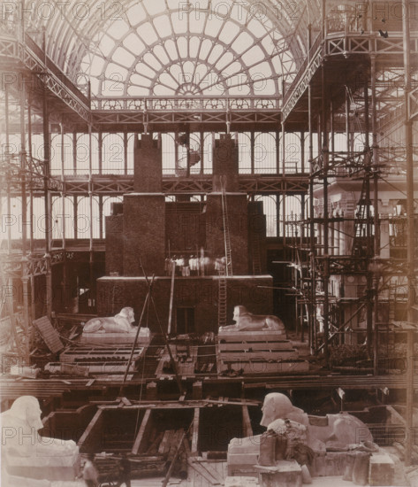 'Preparations for the erection of the Colossi of Aboo Simbel', Crystal Palace, Sydenham, 1852-1854. Designed by Sir Joseph Paxton to house the Great Exhibition of 1851 in Hyde Park, the Crystal Palace was reconstructed and enlarged in Sydenham in 1852. The first column was raised on 5 August 1852 and the palace was opened by Queen Victoria on 10 June 1854. Many exhibitions and events were subsequently held at the Crystal Palace until it burnt down on 30 November 1936. The park contained a motor racing circuit from 1937 until 1972 and the famous athletics track dates back to the foundation of the Crystal Palace Athletics Club in 1868. Plate 39 from "Photographic Views of the Progress of the Crystal Palace, Sydenham. Taken during the progress of the works, by desire of the directors, by Philip H Delamotte. Together with a list of the directors and officers of the company, etc". [London, 1855].