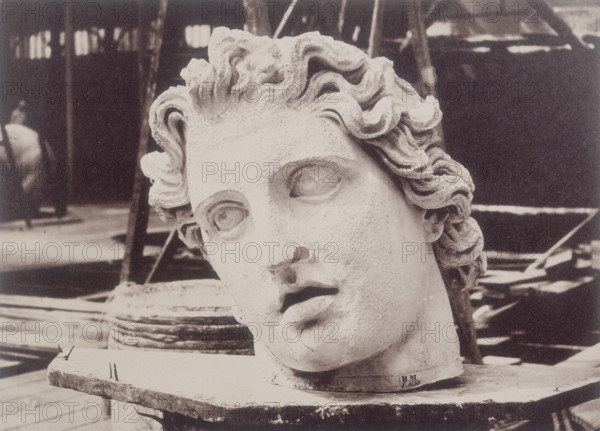 'Head from one of the Colossi of Monte Cavallo, Rome, by Phidias', Crystal Palace, 1852-1854. Designed by Sir Joseph Paxton to house the Great Exhibition of 1851 in Hyde Park, the Crystal Palace was reconstructed and enlarged in Sydenham in 1852. The first column was raised on 5 August 1852 and the palace was opened by Queen Victoria on 10 June 1854. Many exhibitions and events were subsequently held at the Crystal Palace until it burnt down on 30 November 1936. The park contained a motor racing circuit from 1937 until 1972 and the famous athletics track dates back to the foundation of the Crystal Palace Athletics Club in 1868. Plate 54 from "Photographic Views of the Progress of the Crystal Palace, Sydenham. Taken during the progress of the works, by desire of the directors, by Philip H Delamotte. Together with a list of the directors and officers of the company, etc". [London, 1855].