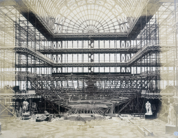 'Erection of the Orchestra for the Opening Ceremony', Crystal Palace, Sydenham, 1852-1854. Designed by Sir Joseph Paxton to house the Great Exhibition of 1851 in Hyde Park, the Crystal Palace was reconstructed and enlarged in Sydenham in 1852. The first column was raised on 5 August 1852 and the palace was opened by Queen Victoria on 10 June 1854. Many exhibitions and events were subsequently held at the Crystal Palace until it burnt down on 30 November 1936. The park contained a motor racing circuit from 1937 until 1972 and the famous athletics track dates back to the foundation of the Crystal Palace Athletics Club in 1868. Plate 85 from "Photographic Views of the Progress of the Crystal Palace, Sydenham. Taken during the progress of the works, by desire of the directors, by Philip H Delamotte. Together with a list of the directors and officers of the company, etc". [London, 1855].