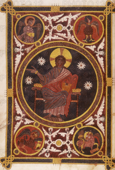 Christ in majesty, 1109. Set within a circle, his right hand raised in blessing, and holding a book in his left hand. In the background are four stars. With stylised floral borders and Celtic knot patterns. In the corners are four roundels with the symbols of the evangelists: angel, eagle, bull and lion. Around these are pairs of coiled serpents and human heads with foliate motifs emerging from their mouths. From the Silos Apocalypse.
