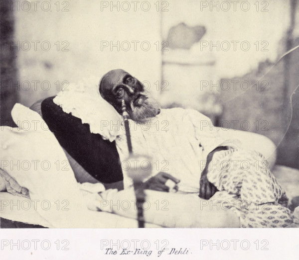 'The Ex-King of Delhi', Bahadur Shah II, 1858. Portrait of Bahadur Shah II (1775-1862), also known as Abu Zafar Sirajuddin Muhammad Bahadur Shah Zafar, Emperor of Delhi 1837-1857, the last of the Mughal emperors in India. He is shown lying on a charpoy with a hookah in front of him. The photograph was taken in May 1858, while the ex-king was being held in Delhi awaiting his trial by the British for his part in the rebellion. It was, apparently, common practice for Europeans to visit the ex-King in captivity: 'While waiting for these charges to be considered the King continued to be displayed to European visitors as one of the curiosities of Delhi. One of those who inspected him was William Hodson's wife who found him, as most other spectators did, lying on the grass ropes of his bamboo charpoy smoking a hookah...'. From "Album Of Portraits. The collection of Thomas George Glover (Bengal Engineers)".