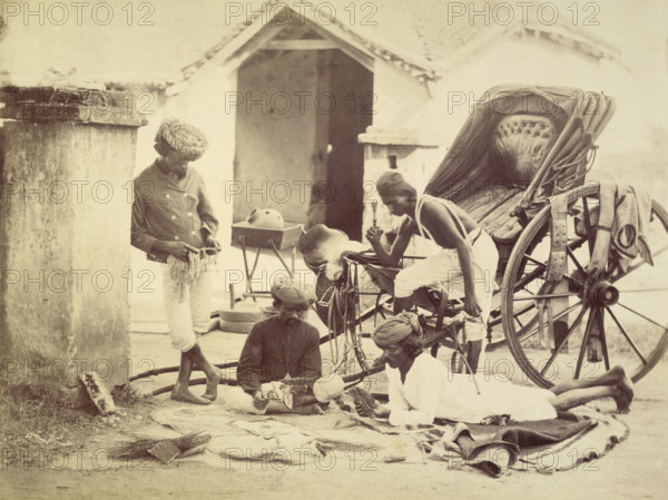 Four men and a rickshaw, India, 1873. Two are playing cards. The man on the right holds a chillum, and the man on the left may be cleaning a horse's bit.