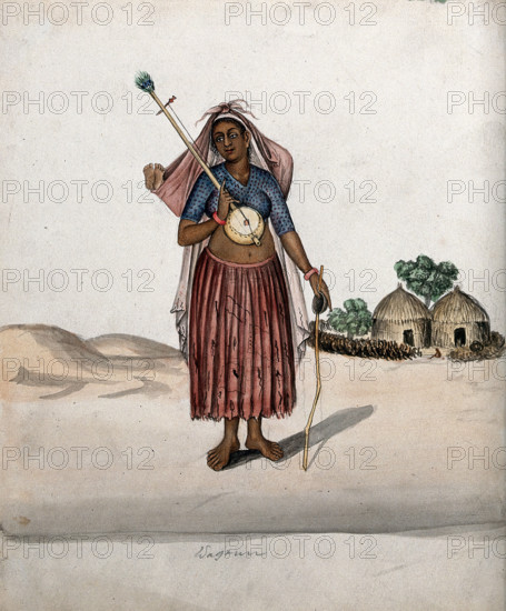 A village woman carrying a musical instrument in one hand, a stick with..., (between 1800 and 1899?) Creator: Unknown.