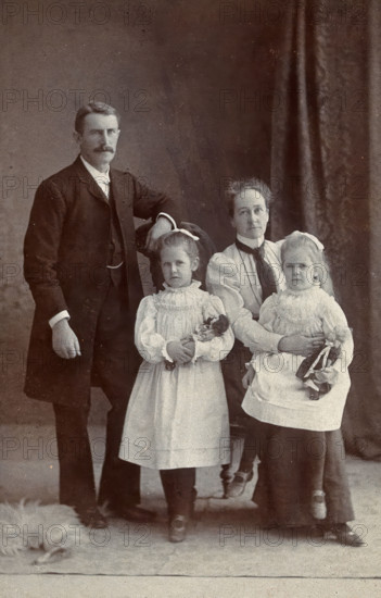 Unidentified family with two girls holding dolls. Creator: Priyalalls Photography.