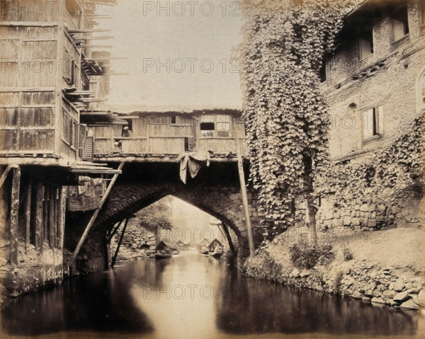 Kashmir: a built-over bridge on a canal betweeen houses, c1870s. Creator: Samuel Bourne.