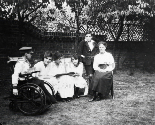 A physically disabled boy sitting in a wheelchair in a garden, c1910/1925. Creator: Unknown.