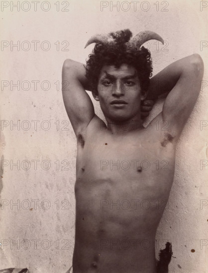 A Sicilian boy naked from the waist up, his hands behind his head, wearing horns, 3 Feb 1899. Creator: Count Wilhelm von Gloeden.