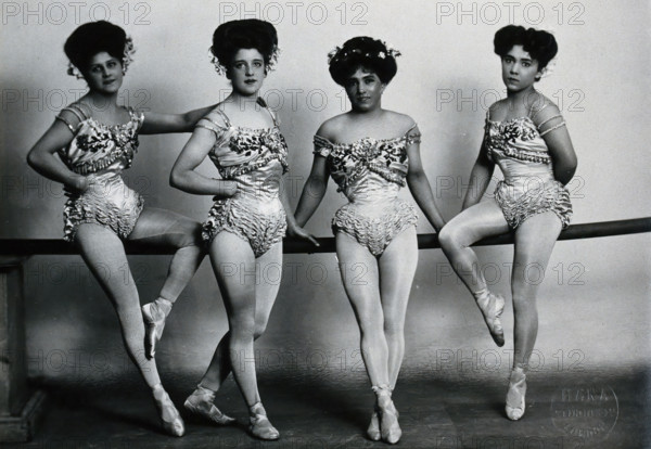 Four young woman acrobats (?), posing on a bar in a photographic studio, between 1899 and 1908. Creator: Unknown.