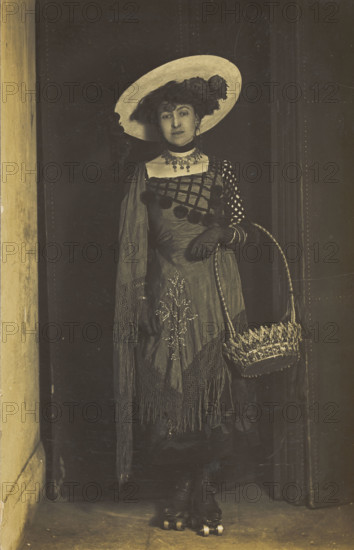 A person wearing a dress, large hat and roller skates, poses holding a basket, (1910-1919?). Creator: Unknown.