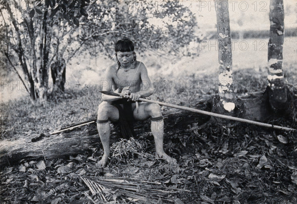Sarawak: a Kenyah worker tying a spearhead to a blowpipe, c1900. Creator: Unknown.