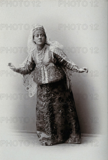 A woman posing in a photographic studio, wearing an embriodered dress, c1900s. Creator: Unknown.