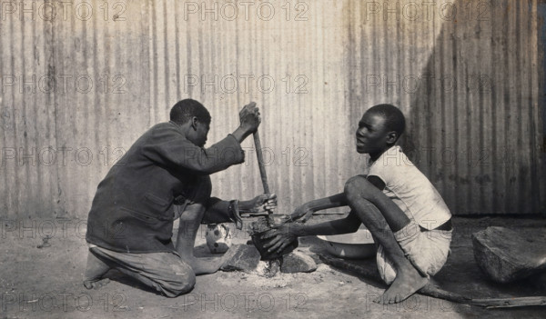 Umtali, Zimbabwe: two African boys stirring a cooking pot, 1905. Creator: J Lomas.