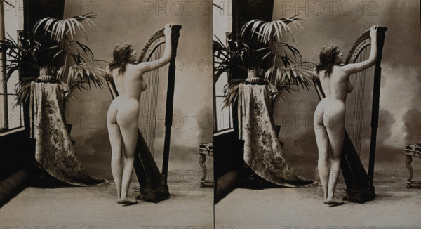 A young woman posing naked in a photographic studio, standing with her back to the camera..., c1900. Creator: Unknown.