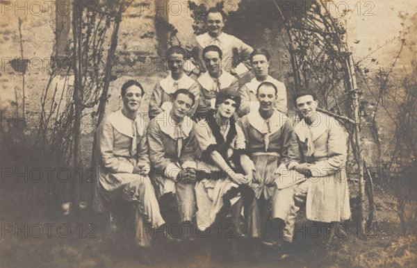 Concert party performers, one in drag, pose for a group portrait, (between 1910 and 1919?). Creator: Unknown.