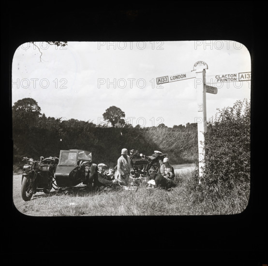 A group of people with two motorcycles and a sidecar having a picnic at the side of..., 1926-1939.  Creator: Norman Kingsley Harrison.