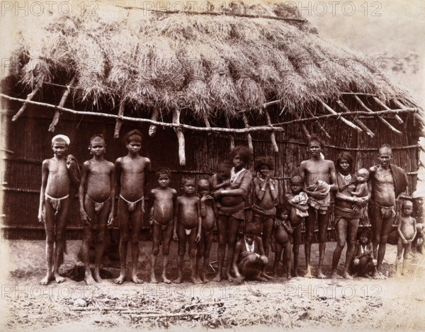 A group of adults and children standing in a line outside a bamboo hut with a thatched..., 1896/1897 Creator: Unknown.