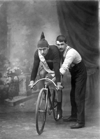 Unknown man on a  bicycle, studio portrait (Championship of Queensland sash/ribbon), 1905. Creator: Robert Augustus Henry L'Estrange.