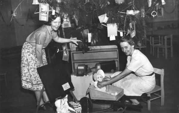 Brisbane Kindergarten Teachers College students/staff with presents and the Christmas tree, 1955. Creator: Unknown.