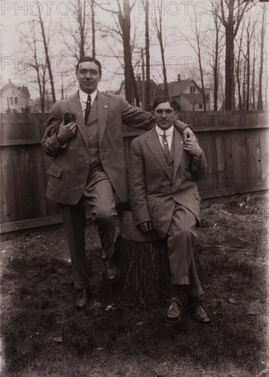 Untitled (two men holding small dog; one sitting on a stump, Fisher St., backyard), c1915. Creator: Wendell Hotter.