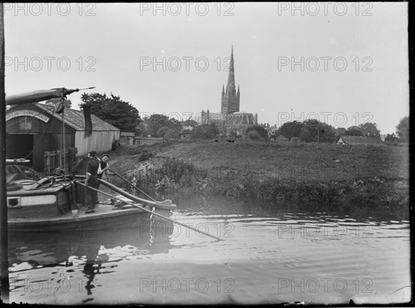 Norwich Cathedral from Pull's Ferry, with men on a boat in the foreground, Norwich, Norfolk, 1920-38 Creator: George R Long.