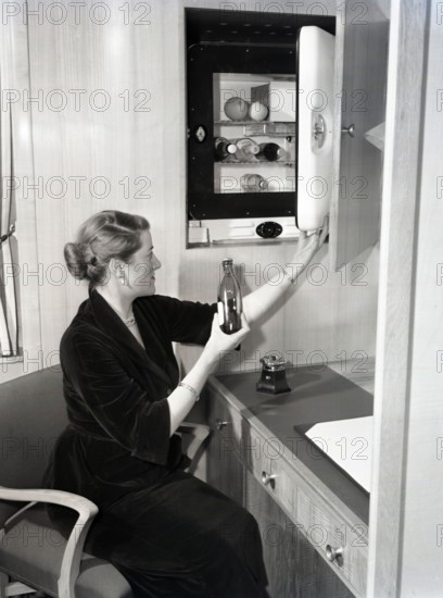 Woman using a compact fridge, possibly on board a ship, c1955.  Creator: Arthur Charles Kirby Ware.