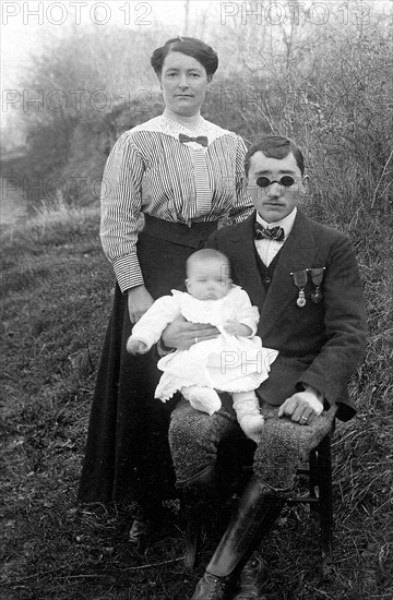 La première guerre mondiale. Un mutilé de la guerre 1914 - 1918, devenu aveugle au combat, pose pour le photographe avec sa femme et son enfant. Gironde fin 1918.