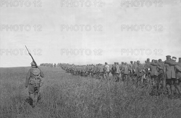 Colonne de prisonniers allemands emmenés vers l'arrière sous la garde d'un soldat américain. - Après la contre offensive franco-américaine du 18 juillet 1918, entre l'Aisne et la Marne.