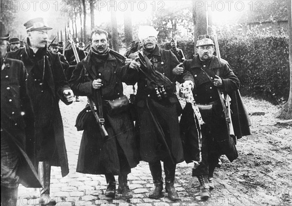 SOLDATS BELGES REVENANT DE LA LIGNE DE DEFENSE D'ANVERS 1914 - En octobre 1914, après la défense d'Anvers  (Belgique), des soldats belges soutiennent l'un des leurs, blessé au front. Ils reviennent de la ligne de défense située derrière la Nèthe. Première Guerre Mondiale -