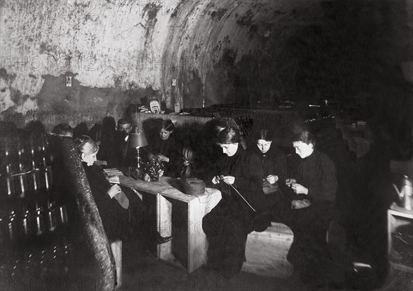 Une famille dans la cave d'une maison de vin de Champagne, à Reims, les femmes tricotent pour les soldats parties sur le front, décembre 1914 - La première guerre mondiale. La vie dans les souterrains des grandes villes bombardées par l'artillerie de l'armée allemande, décembre 1914.