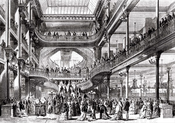Vue en 1872 du grand escalier des magasins du Bon Marché à Paris, après l'achèvement des travaux d'agrandissement de ce qui représente alors le "seul édifice construit et affecté uniquement à l'usage d'un grand commerce de nouveautés".  La date d'inauguration des nouveaux magasins du Bon Marché était fixée au mardi de Pâques 2 avril 1857.  Gravure sur bois de Smeeton d'après Charles Fichot, parue dans L'Illustration du 30 mars 1872.