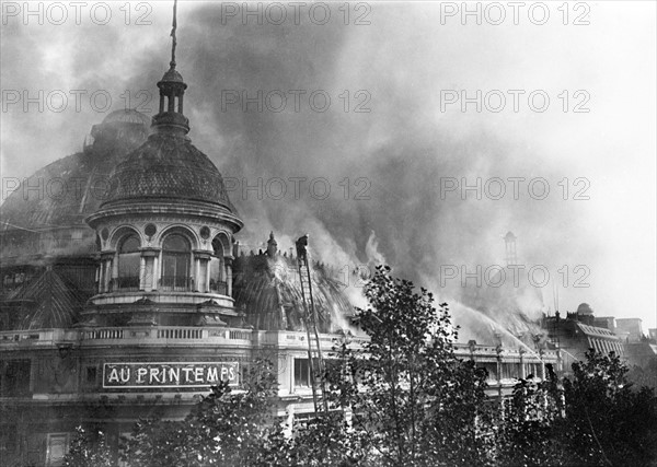 Paris octobre 1521 l'incendie des nouveaux magasins du " Printemps ", du haut de leurs grandes echelles, les pompiers projettent des torrents d'eau sur les combles enflammes de la facade du boulevard Haussmann,