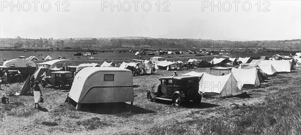 En août 1938, dans l'Orne, les caravanes, tentes et automobiles s'installent sur un terrain de camping.