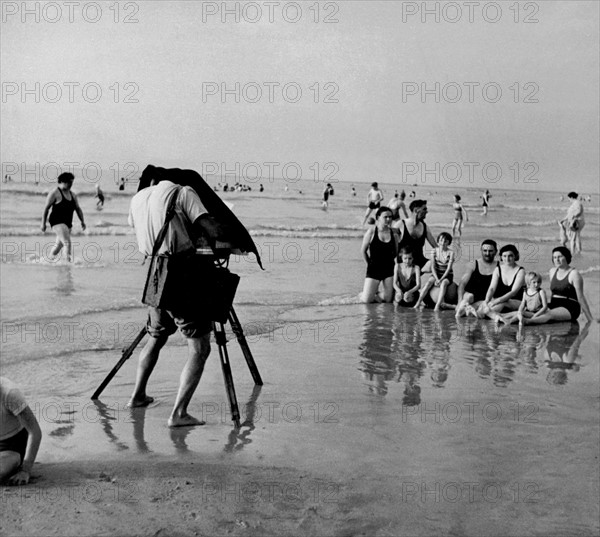 Eté 1951, sur la plage de Deauville, un photographe de plage prend en photo un groupes de baigneurs.