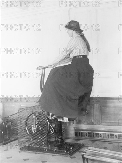 En 1912, séance d'équitation en chambre, dans la salle de gymnastique du majestueux paquebot britannique LE TITANIC. Un moteur électrique intégré à  l'appareil, muni d'une selle et d'étriers, provoque des secousses, qui donnent ainsi l'impression du trot et du galop d'un cheval.  Ces loisirs sont bien évidemment réservés aux passagers de première classe.