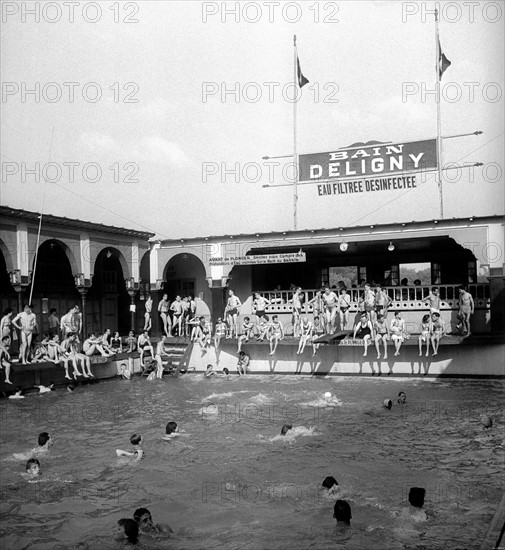 En août 1949, poussés par les grandes chaleurs estivales, les parisiens investissent la piscine DELIGNY (dans le 7ème arrondissement de Paris) sur la Seine.