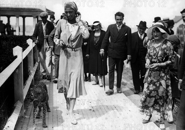 Vers 1930, à Deauville, le jour d'un Grand Prix, l'artiste Joséphine Baker se promène, tenant en laisse un guépard.