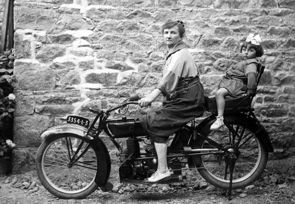 Woman and kid on a motorbike, around 1950