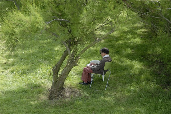 Elderly woman making a drawing in a garden