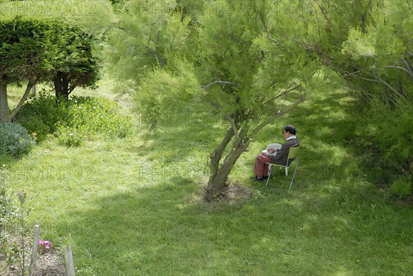 Elderly woman making a drawing in a garden