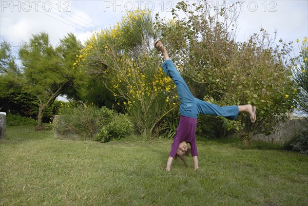 Petite fille faisant la roue dans un jardin