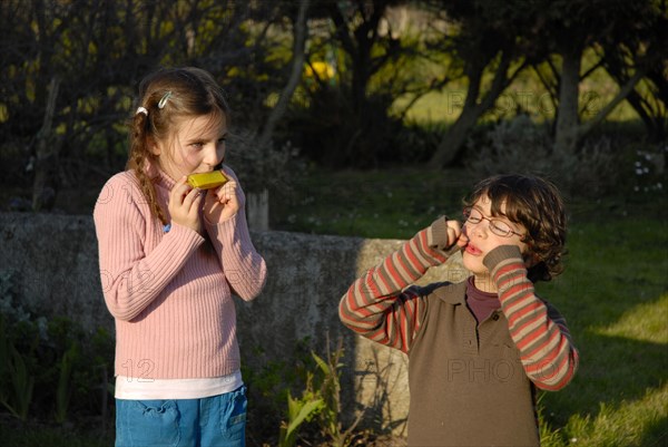 Little girl and boy playing in a garden