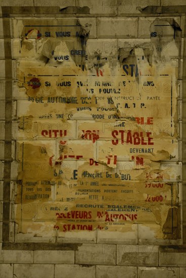Torn poster on a wall in the Paris metro