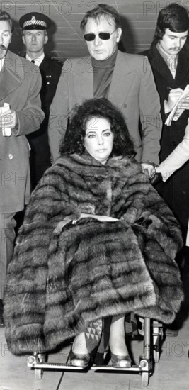Elizabeth TAYLOR in a wheelchair with Richard BURTON, 1973