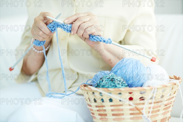 Hands of elderly woman knitting woolen clothes