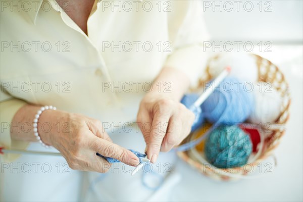 Hands of elderly woman knitting woolen clothes