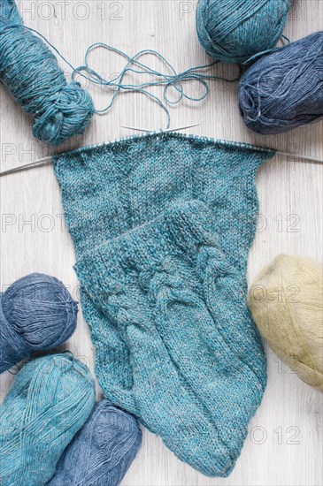 Knitted blue scarf and skeins of wool on the wooden table