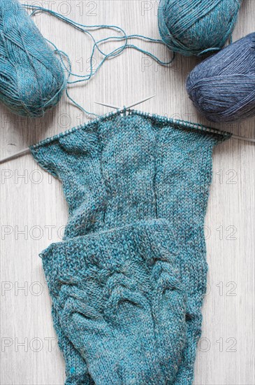 Knitted blue scarf and skeins of wool on the wooden table