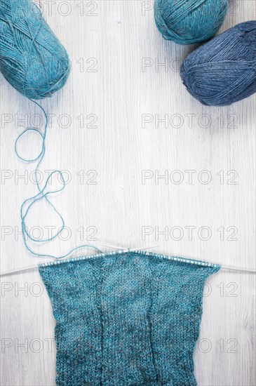 Knitted blue scarf and skeins of wool on the wooden table