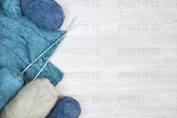 Knitted blue cloth and skeins of wool on the wooden table