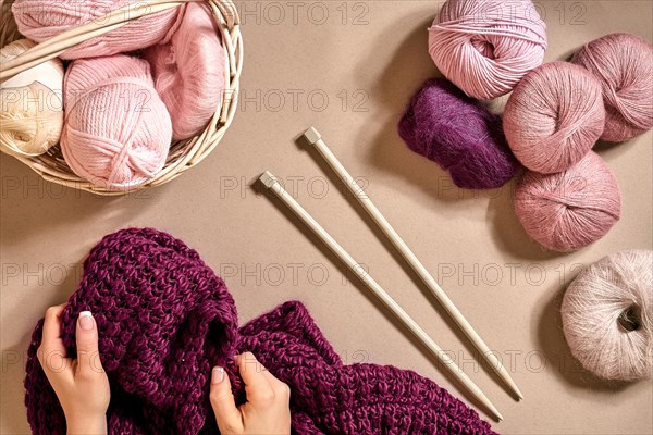 Close-up of female hands knitting wool sweater or plaid lilac color. Top view